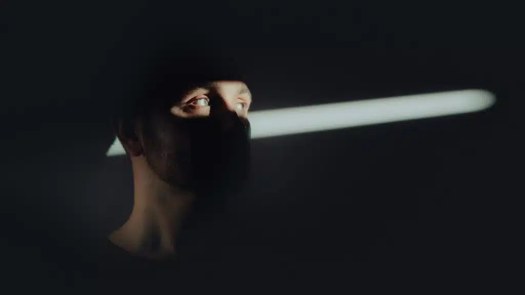 A man whose face is hidden in the shadows and staring to the side.