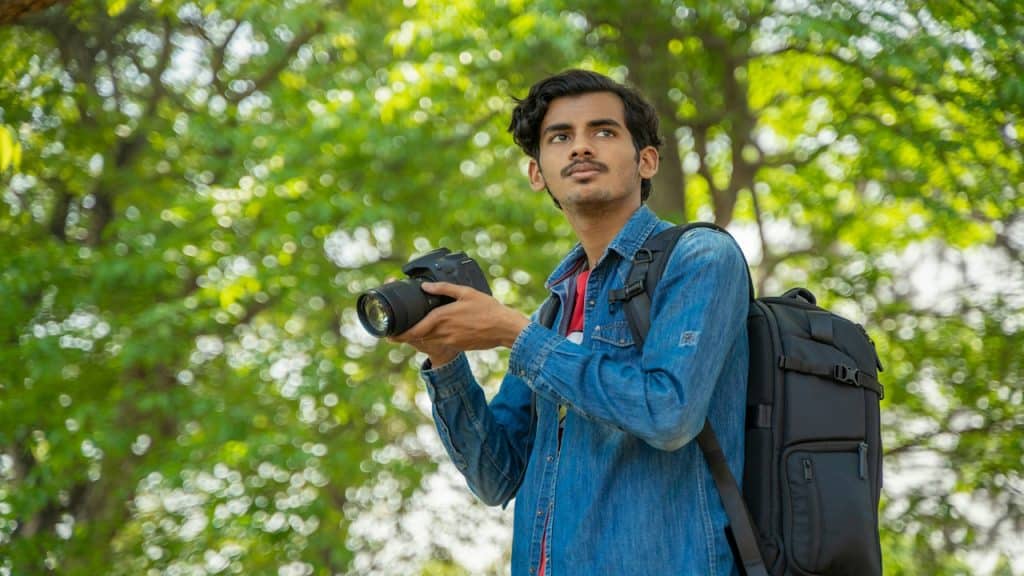 A man holding a camera in an open area.