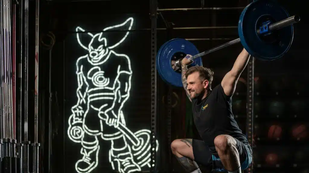 A man squatting with a barbell in his hands.