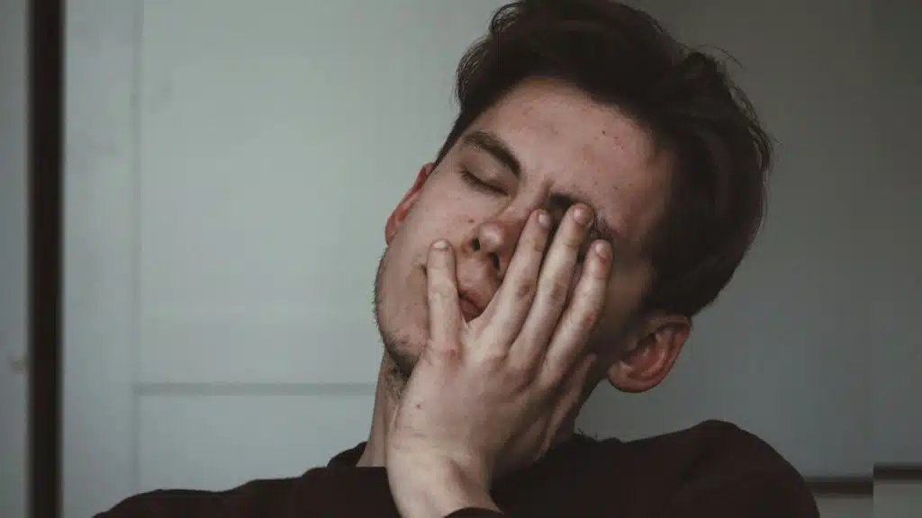 A sad man covering his face with his hand.