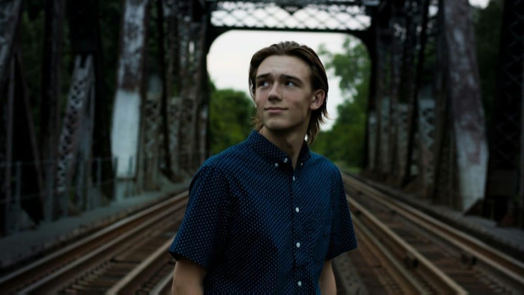 A man standing in the middle of a bridge rail.