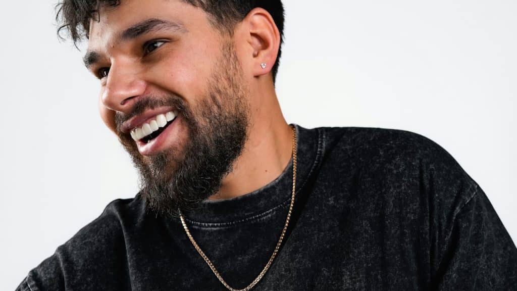 A bearded smiling man wearing a chain