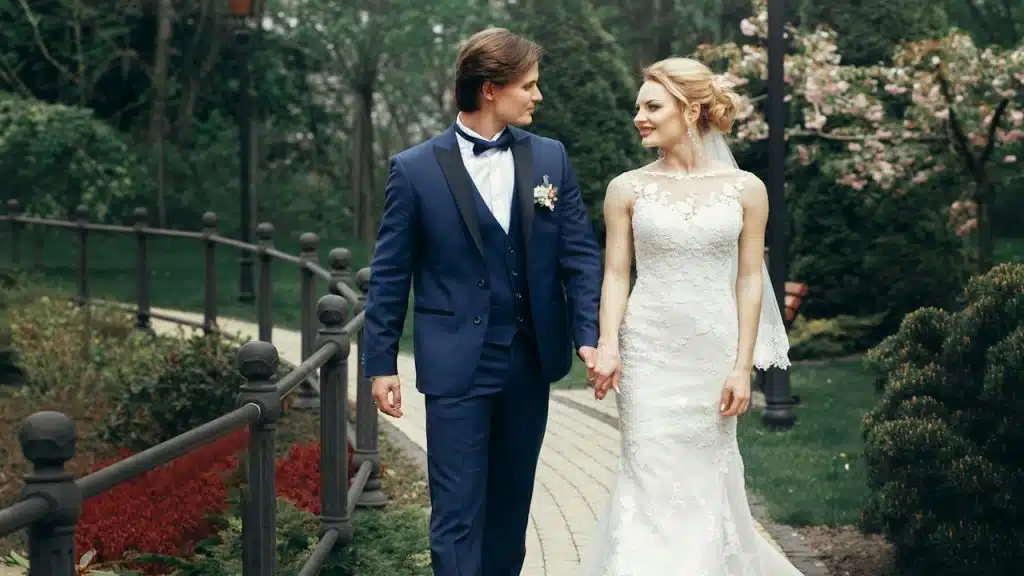 Wedding couple walking and smiling among trees.