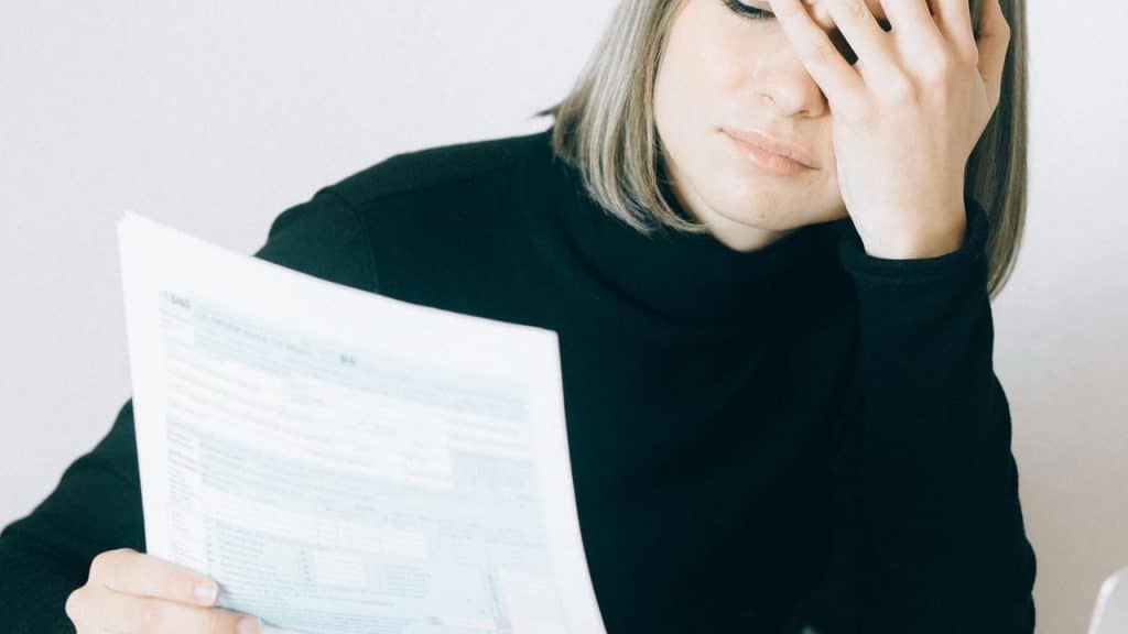 A woman holding a document with a stressed expression.