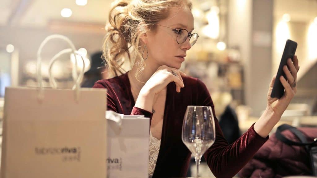 A woman sitting at a table looking at her phone.