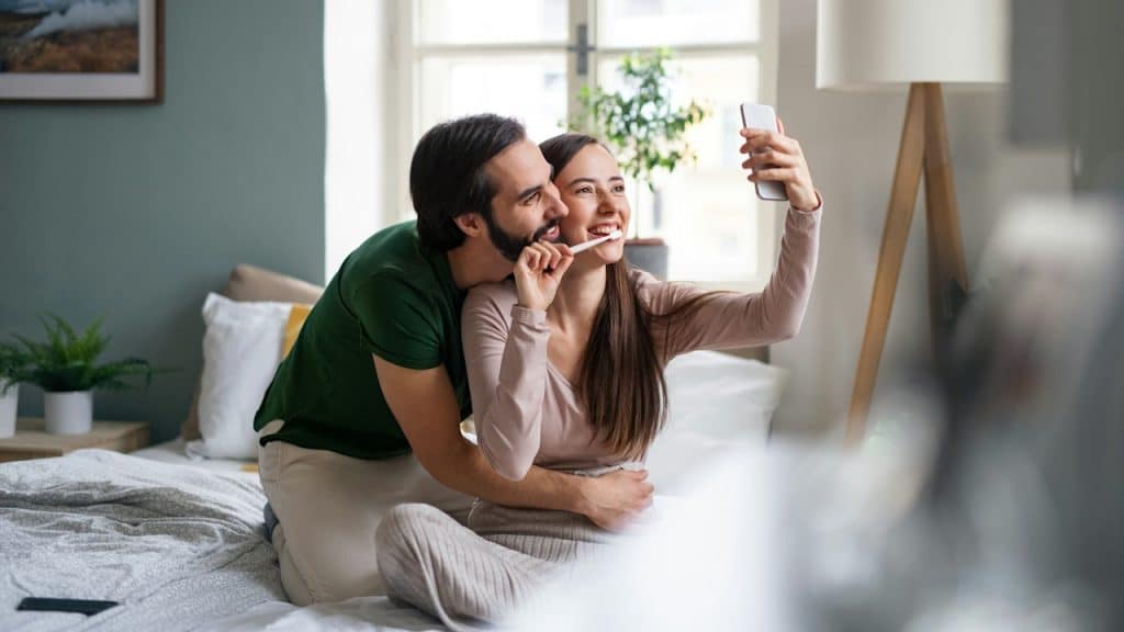 Happy young couple taking a selfie on the bed.