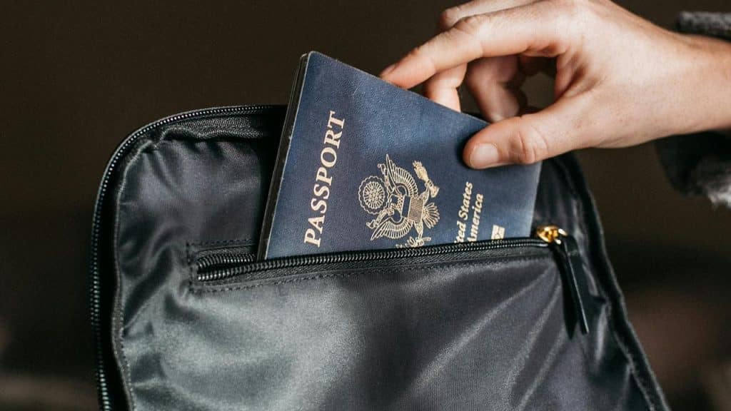 A person placing a US passport into a black bag.