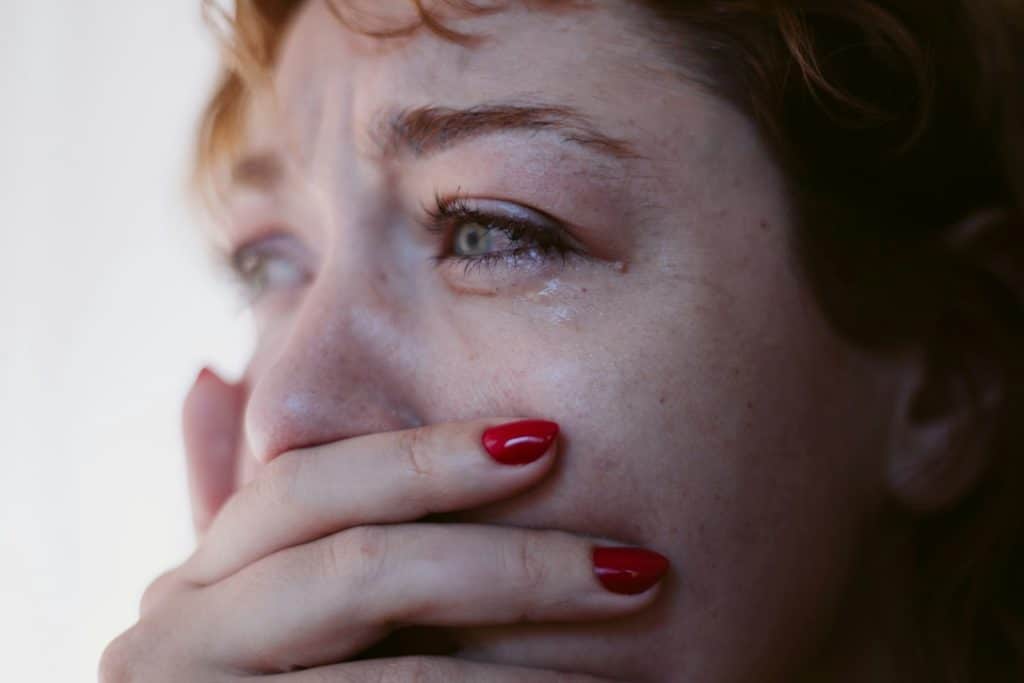 The woman is crying while covering her mouth.