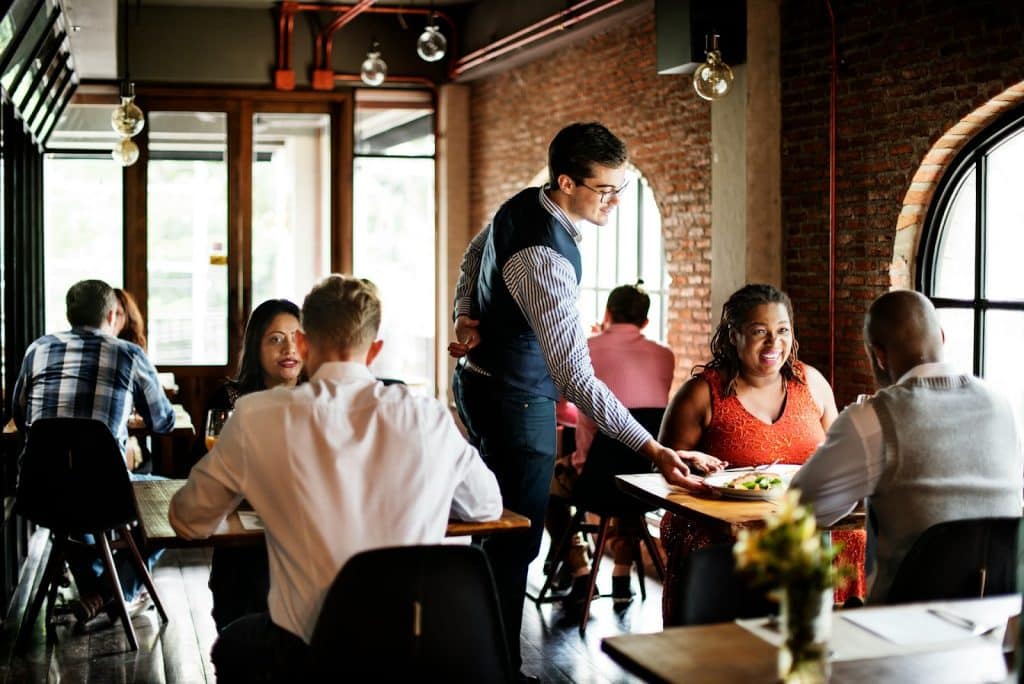 The man is serving food to the couple.