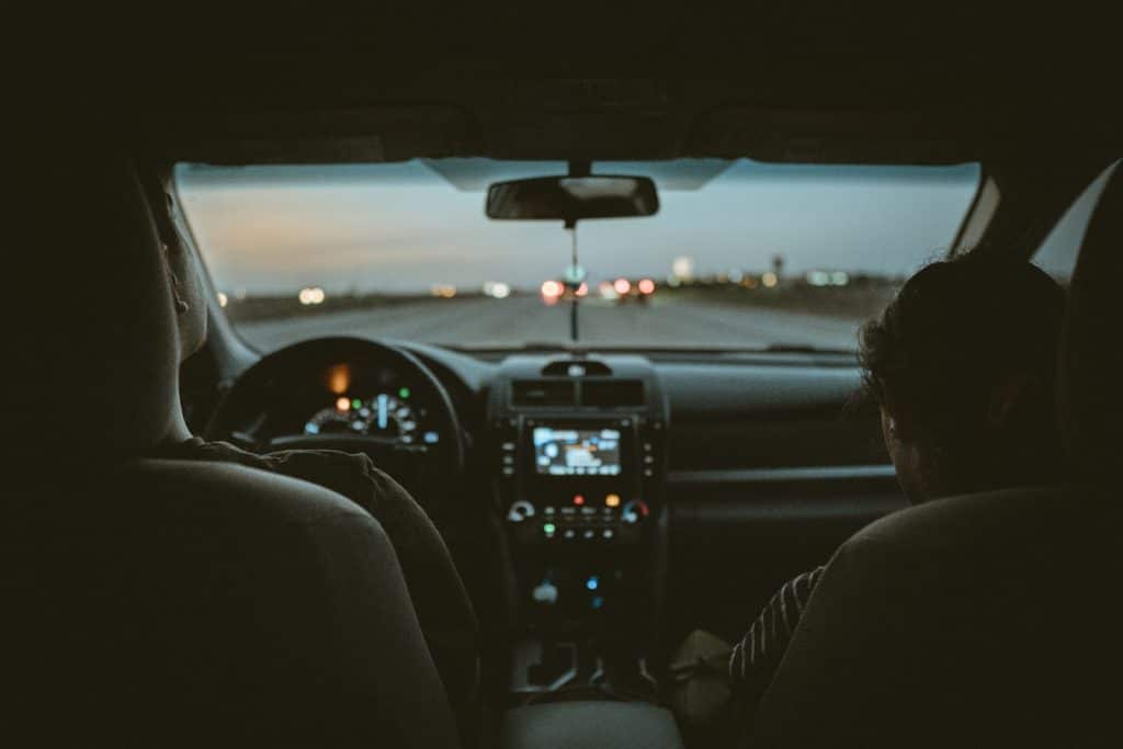A man and a woman in a car driving.