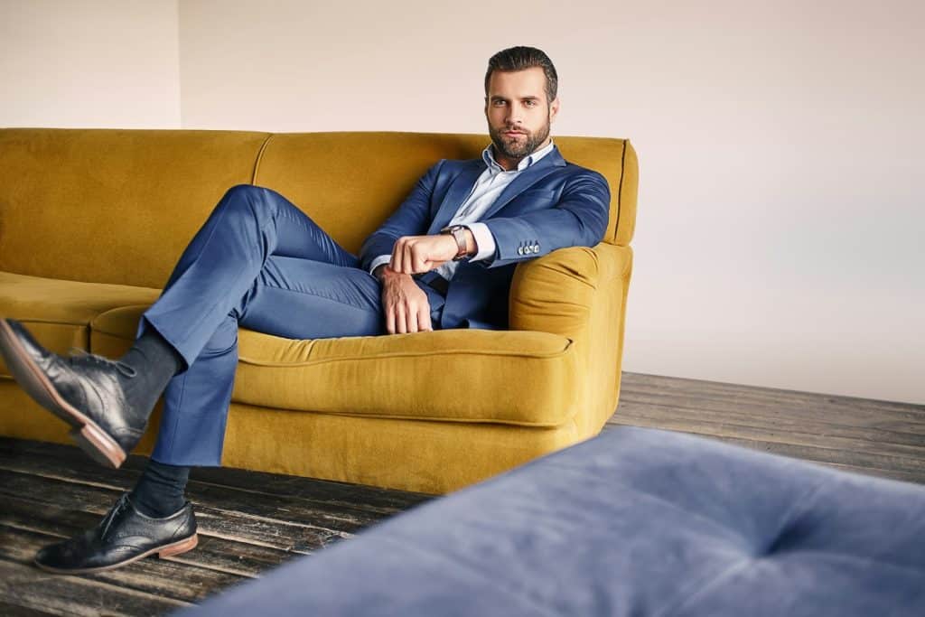 A man in a nice suit sitting in a sofa.