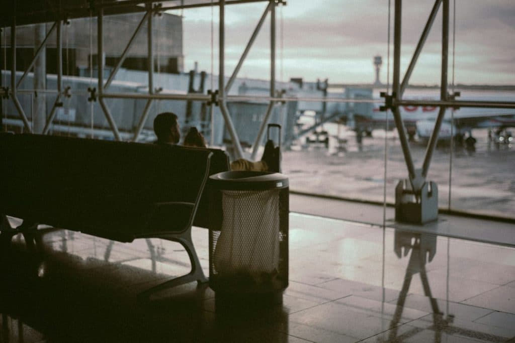 A man in an airport and sitting in the departure area.