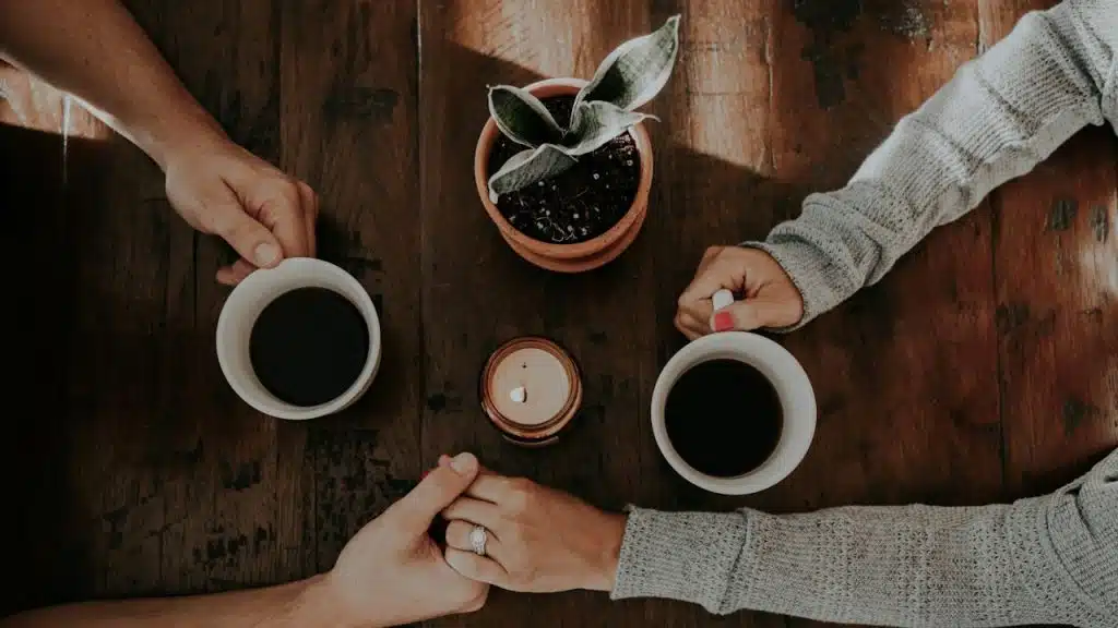 A couple having coffee and holding hands.