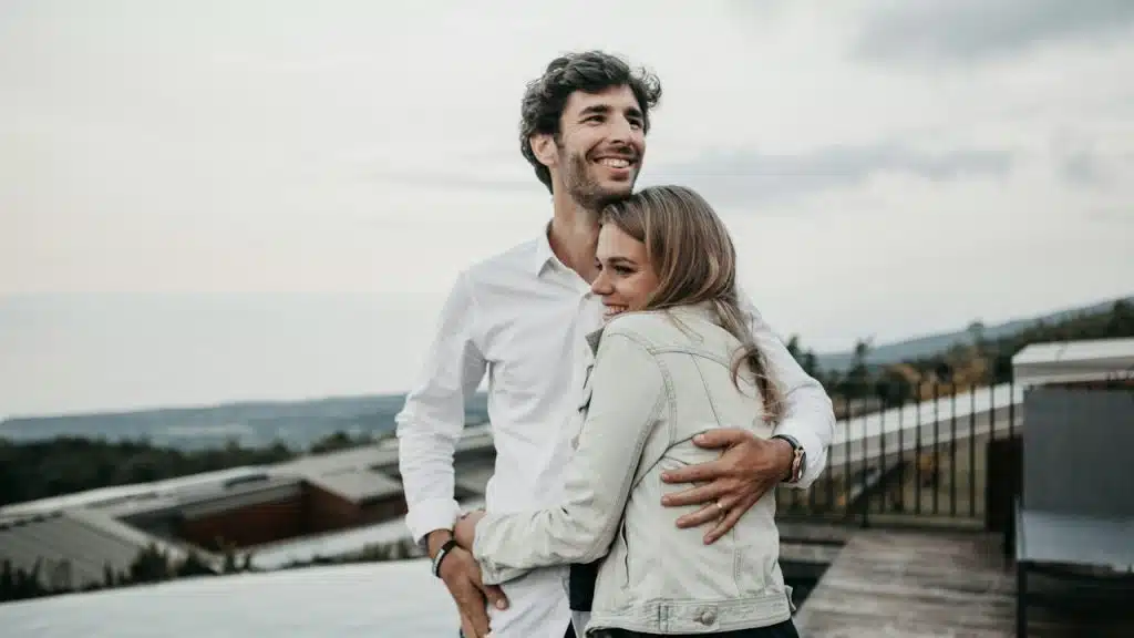 A couple hugging on the top of a building.