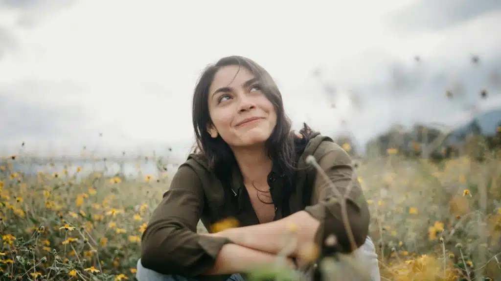 A woman smiling while surrounded by flowers.