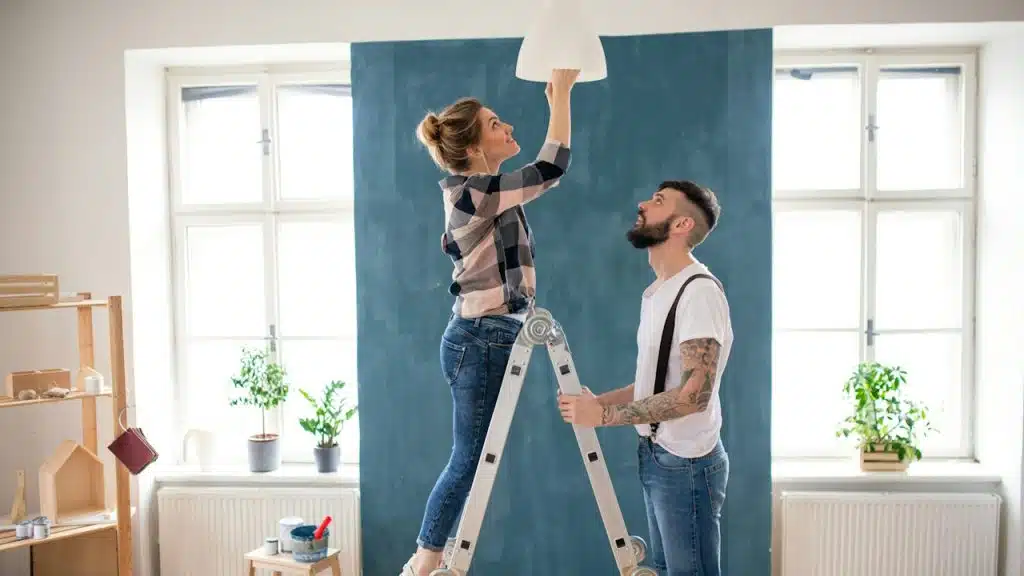 A couple changing a lightbulb together.