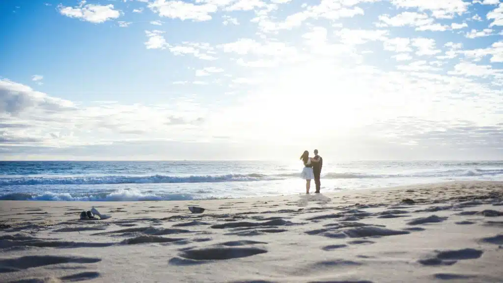 A couple standing by the seaside on the beach.