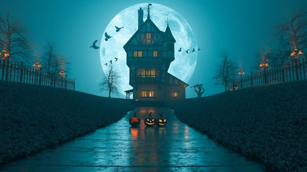 A walkway leading to a haunted house with jack-o-lanterns placed in the middle.