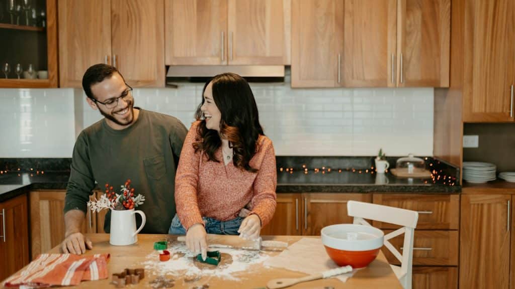 A couple baking together in the kitchen and laughing.
