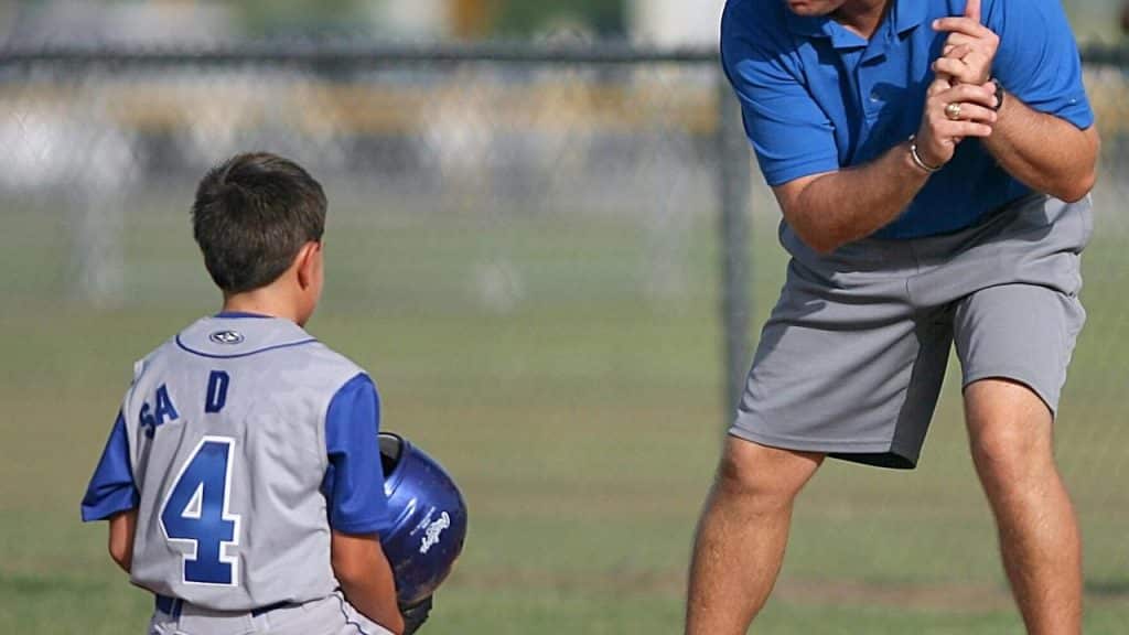 A father giving instructions to his son on the baseball field.