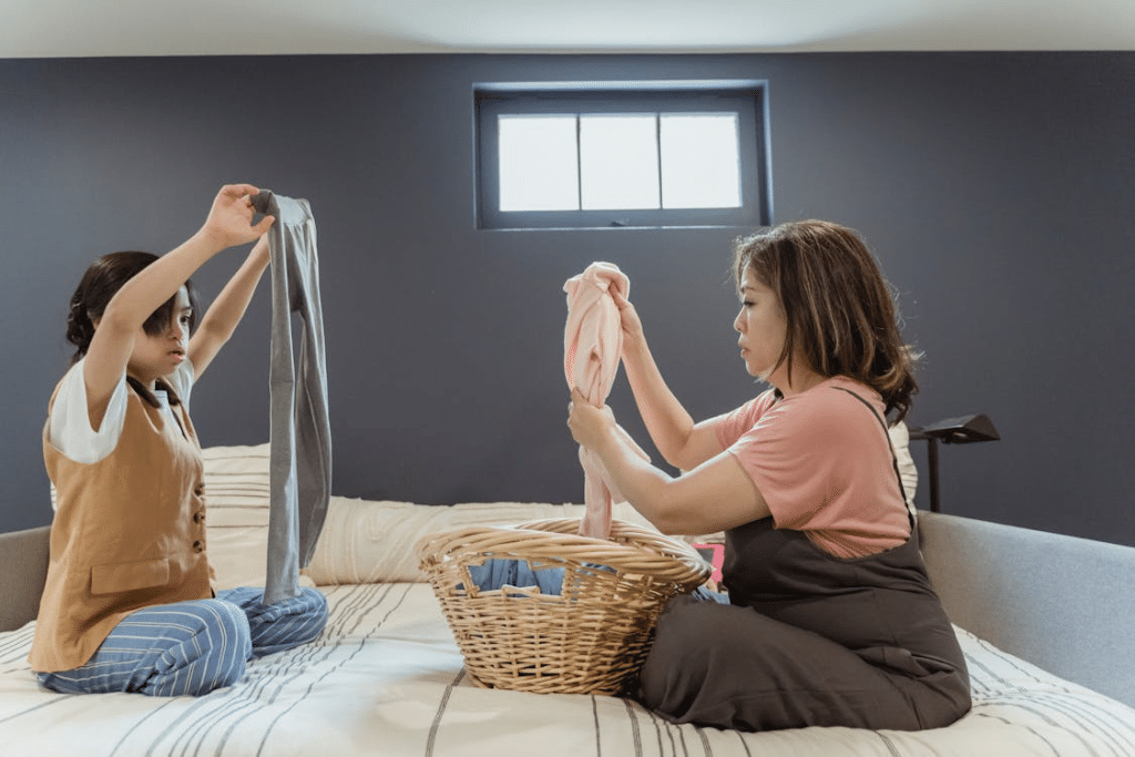 A Mother and Daughter Sitting on the Bed while Holding Clothes