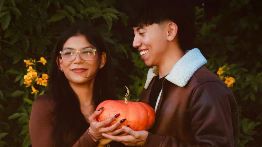 A smiling couple holding a pumpkin.