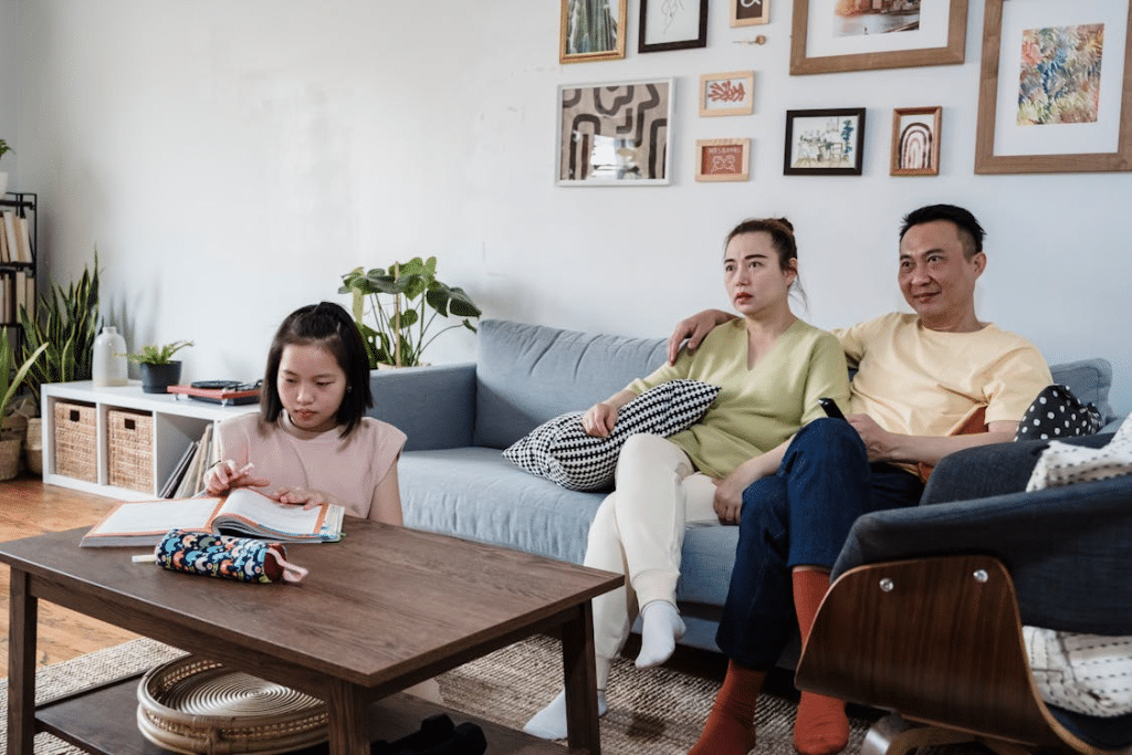Man and Woman Sitting on Couch while a Girl Studying on the Table