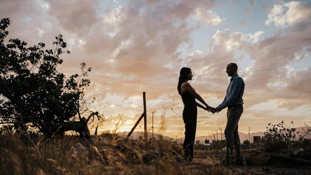 A man and a woman holding hands in a field.