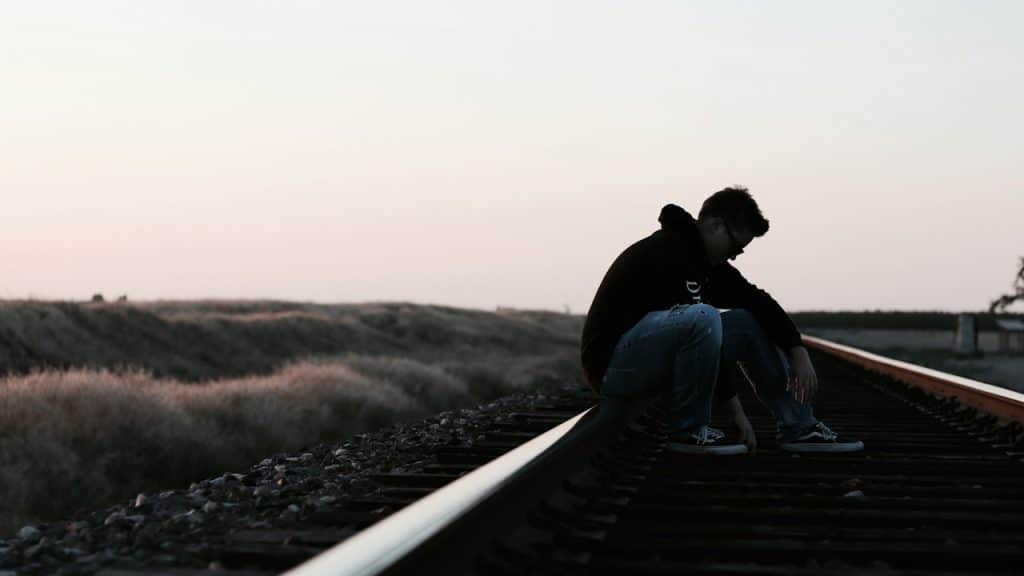 A man sitting on a train track.