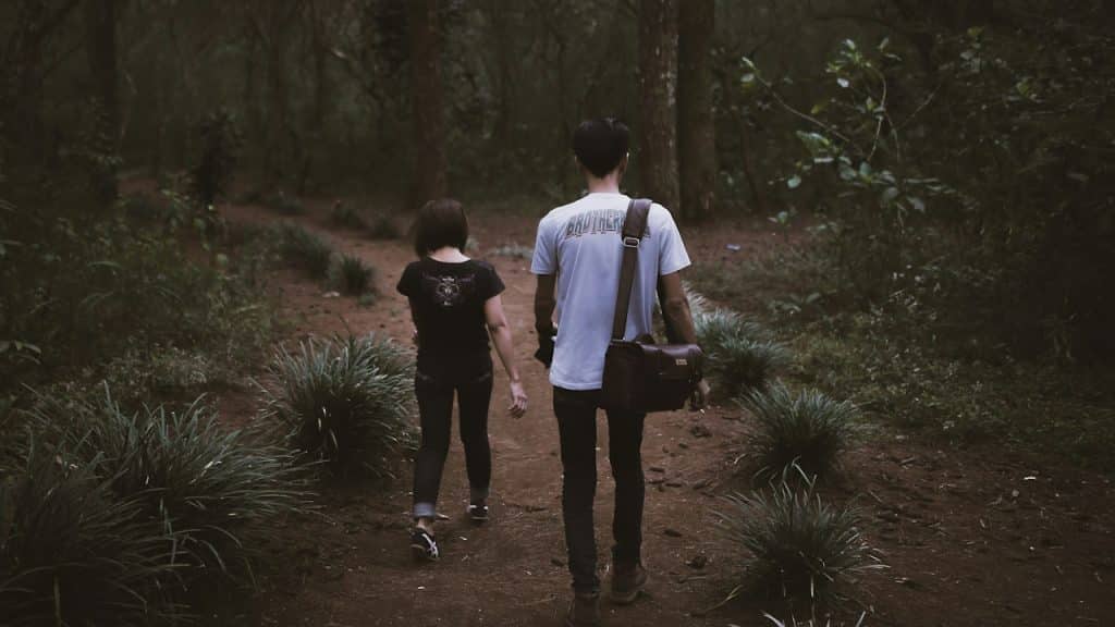 A woman going away from her boyfriend while walking in a forest.
