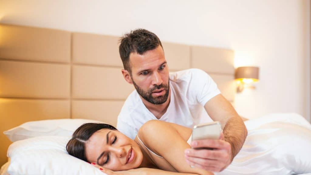 Husband spying on his partner's phone while she is sleeping.