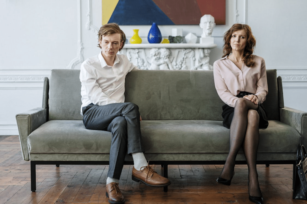 Woman in White Dress Shirt and Black Pants Sitting on Gray Couch