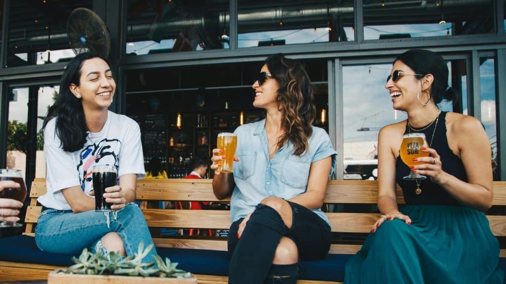 A group of friends laughing and enjoying drinks at an outdoor bar.