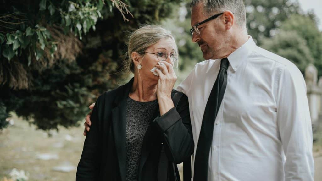 A grieving couple comforting each other at a funeral.
