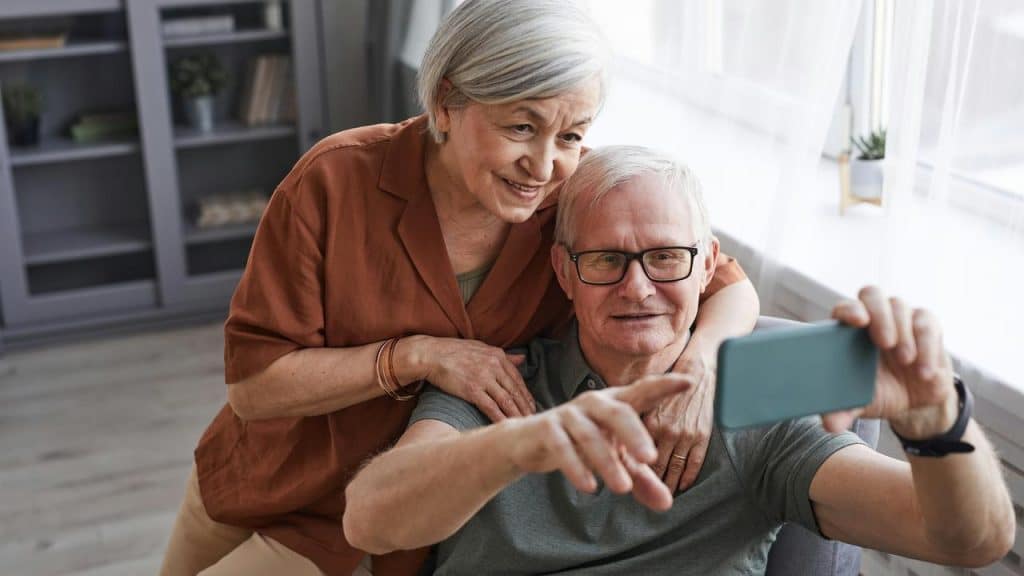 An elderly couple taking a selfie together and smiling.