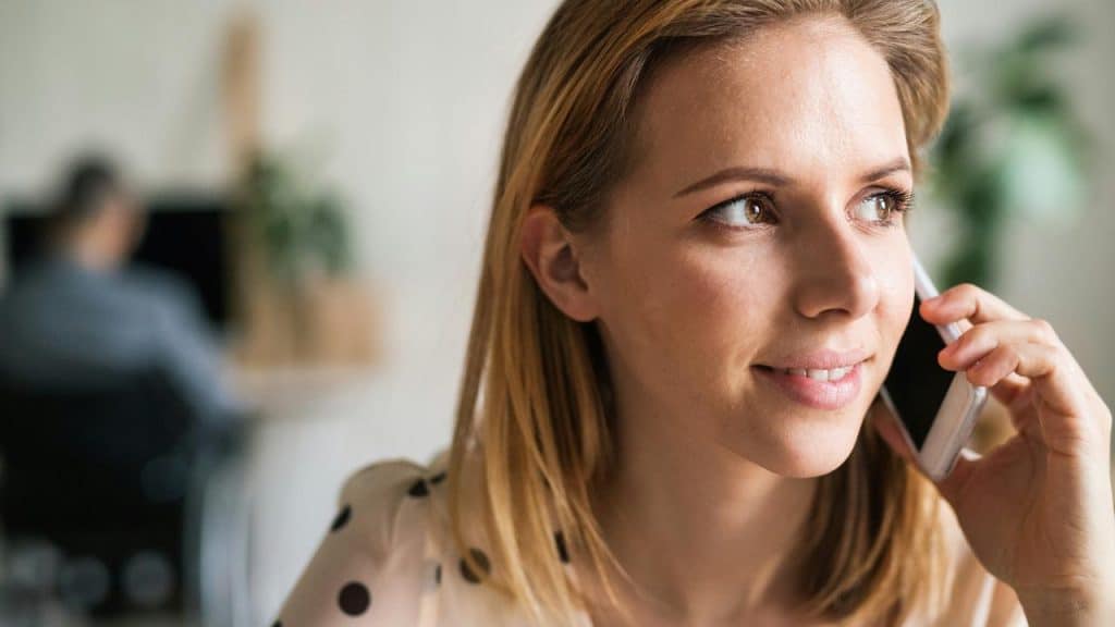A woman smiling while talking on a smartphone.