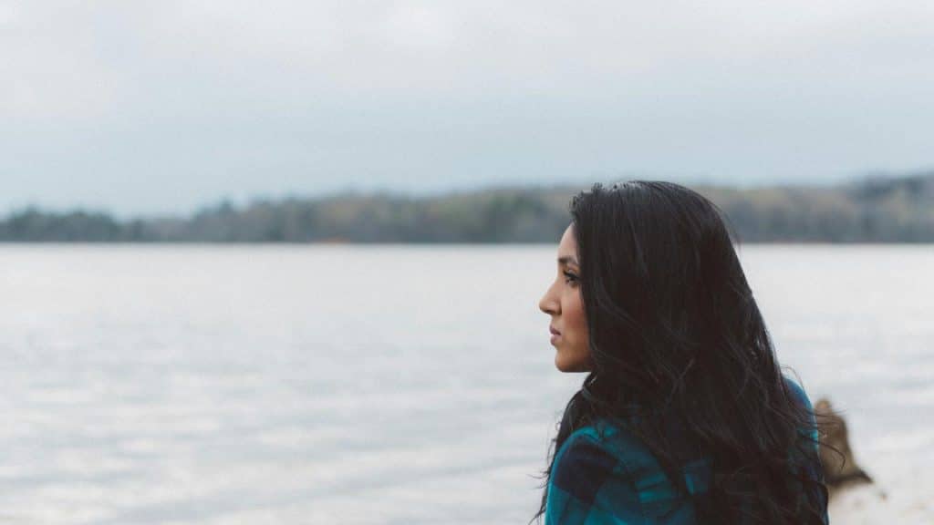 A woman standing by the water looking out at the lake.