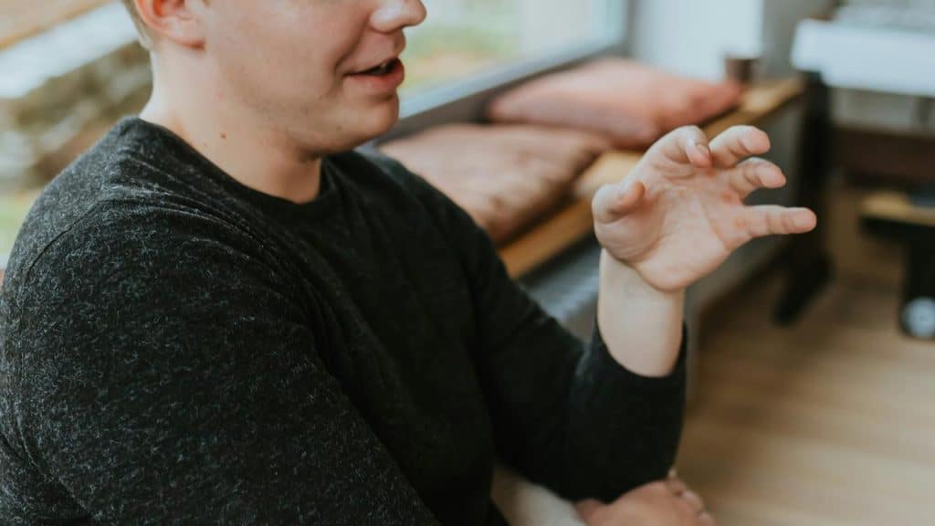 A man gesturing with his hand while talking indoors.