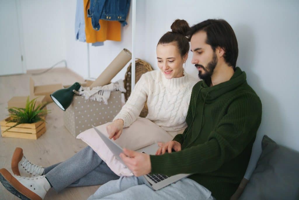 The woman is pointing at the laptop’s screen.