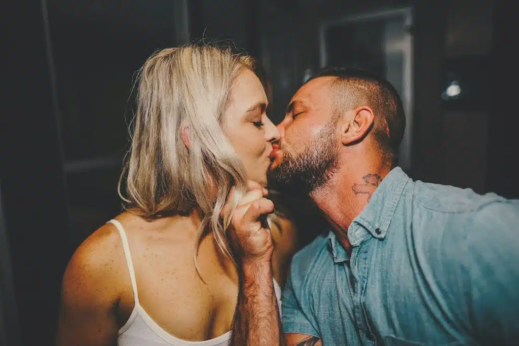 The man in the blue shirt is kissing the woman.