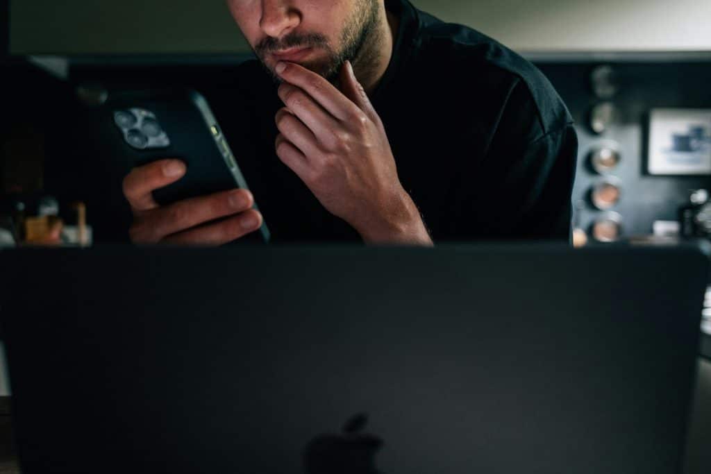 The man is looking at his phone with a serious expression.