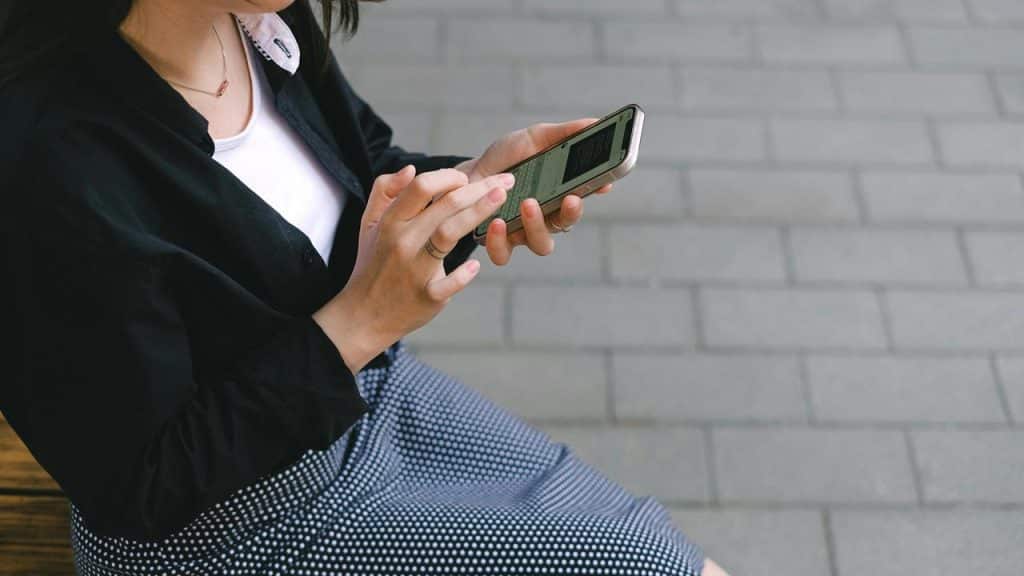 A woman using her smartphone while sitting outside.