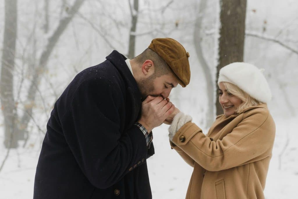 A man and woman kissing a woman’s hands