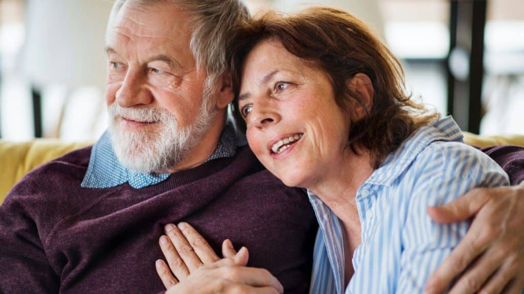 Smiling senior woman with her head resting on a bearded man's shoulder.