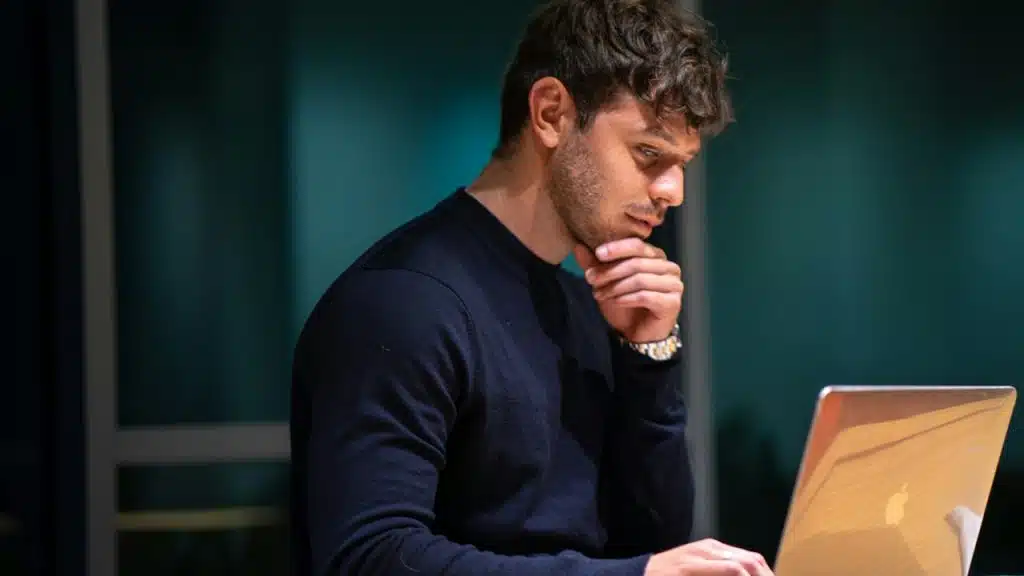 A man working on a laptop and thinking about something.