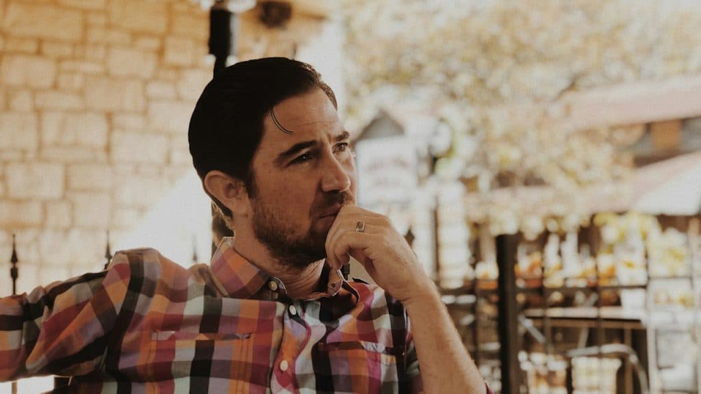 A lightly bearded man lost in thought.