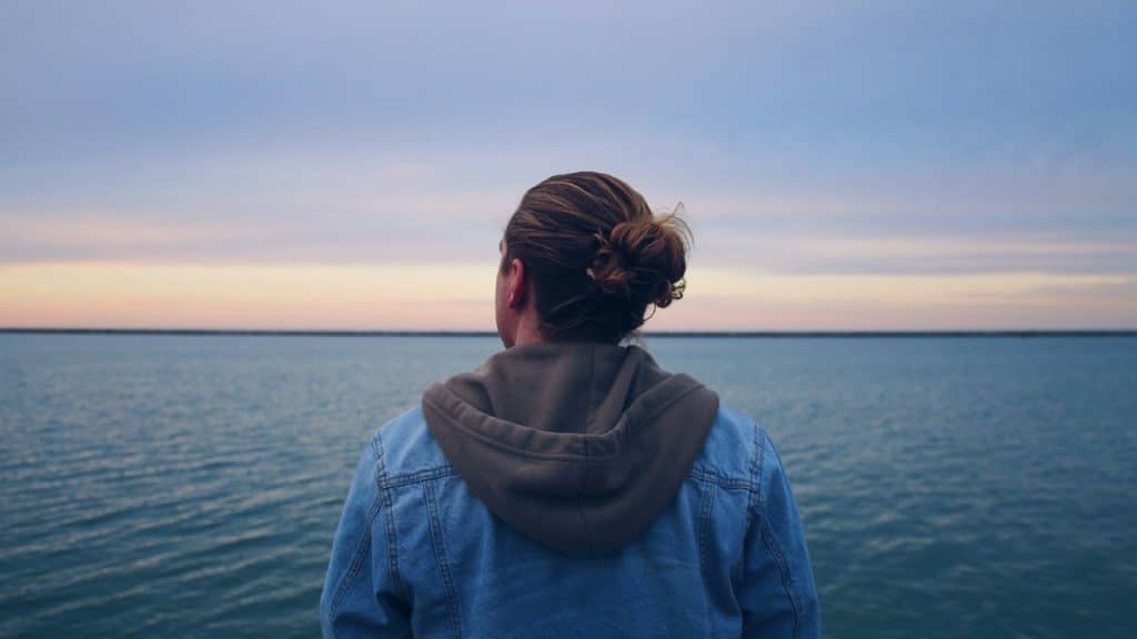 A person looking towards the horizon while standing by the seaside.