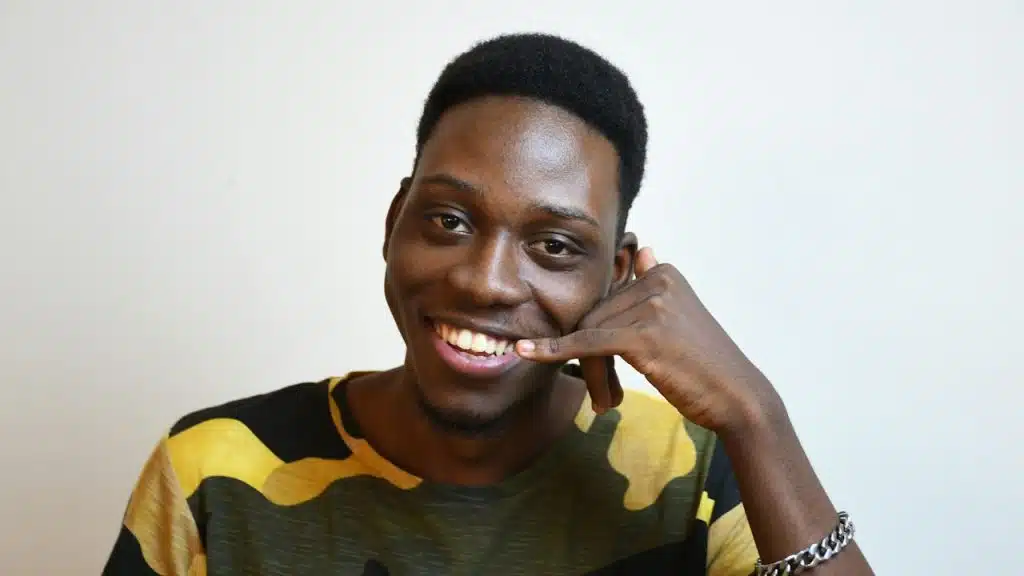 A smiling man using the “call me” gesture.