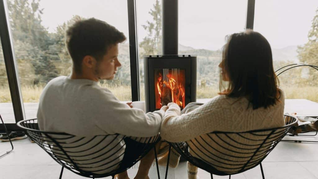 A couple warming their hands in front of a heater in winter.