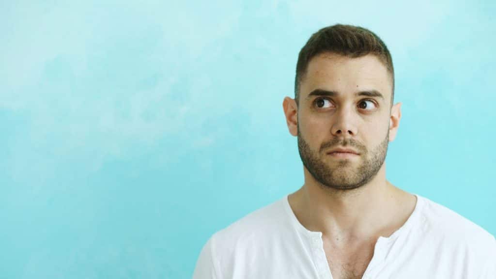 A man looking away from the camera in a blue background.